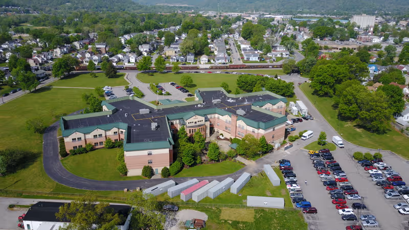 Aerial view of Rosedale Green senior living campus with connected beige buildings and parking.