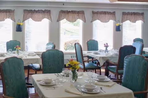Bradford Square dining room with set tables, green chairs, and floral centerpieces.