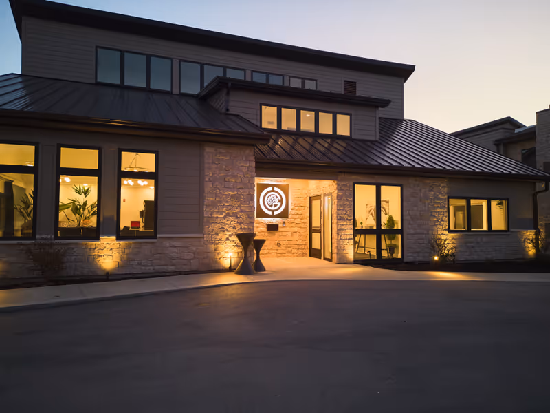 Exterior of a modern senior living facility at dusk with illuminated entrance.