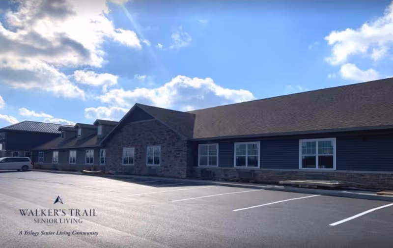 Exterior view of Walker's Trail Senior Living building with parking lot and blue sky.