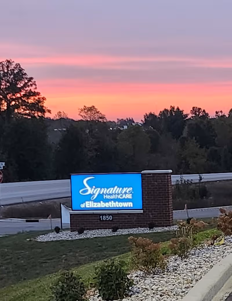 Exterior Signage for Signature HealthCARE of Elizabethtown along road at sunset.