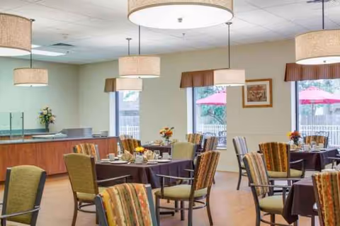 Interior dining room in a senior living facility with round tables and chairs.