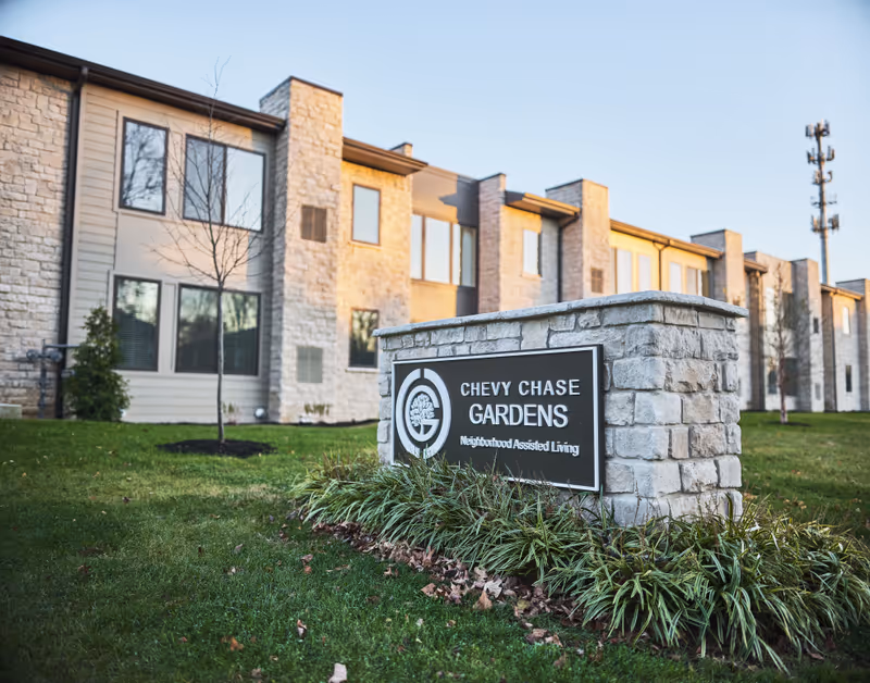 Exterior view of a senior living facility with a stone sign in front.
