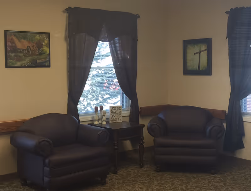 Two dark leather chairs flank a small table in a cozy living room.