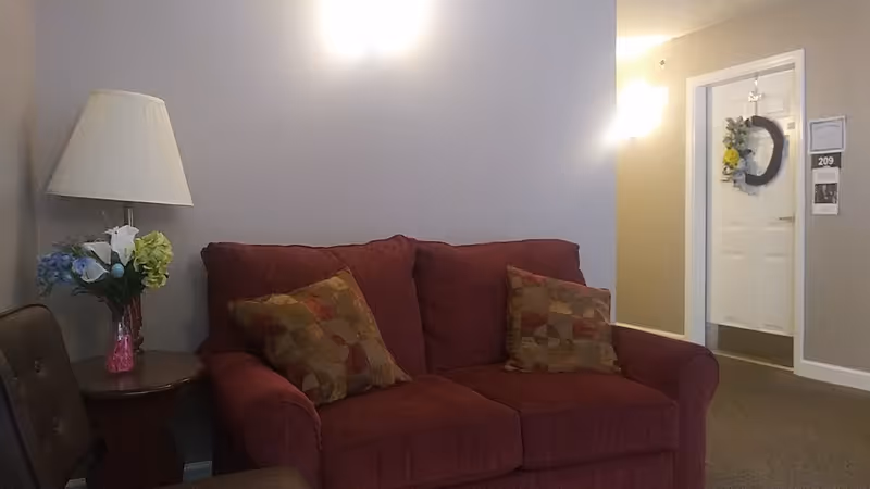 A red sofa with patterned pillows in a cozy living room of a senior housing unit.