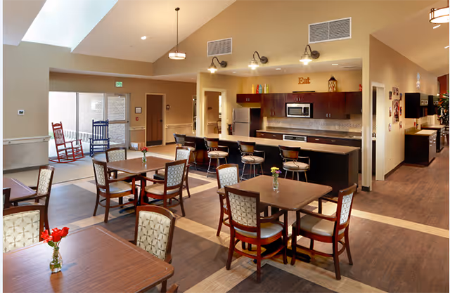Bright dining area with tables, chairs, and a bar-style counter in Hallmark House.