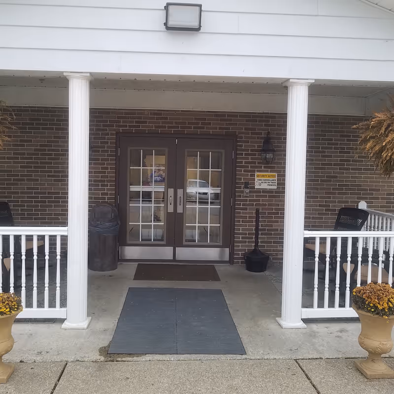 Exterior entrance with brick wall, double glass doors, and white columns.