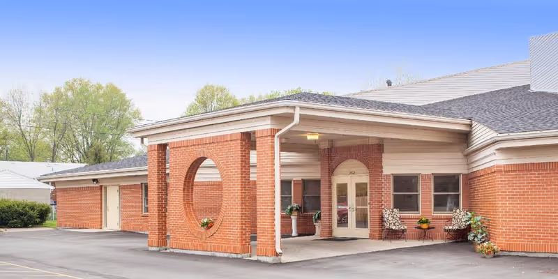 Front entrance of a single-story brick senior living facility with a covered portico and a decorative circular brick opening.