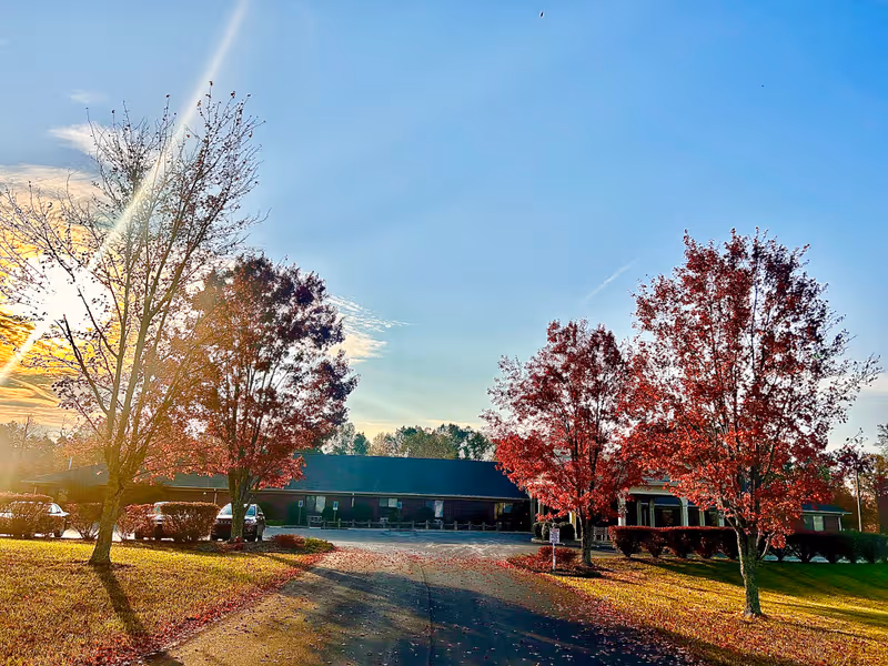 Exterior view of Edgewood Estates facility with trees, parking lot, and blue sky.