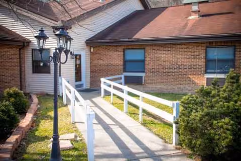 Front entrance of Signature HealthCARE of Spencer County with white railing ramp and lamp post.