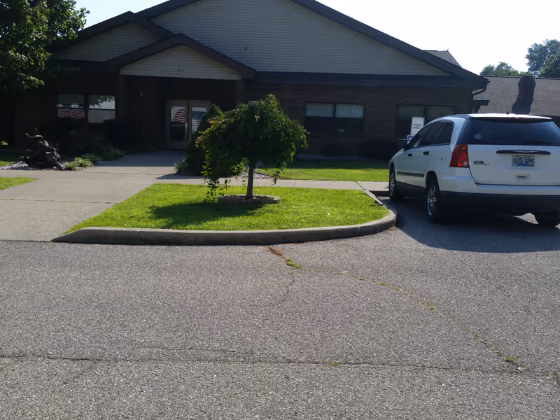 Exterior view of Gallatin Nursing and Rehabilitation entrance with a white SUV parked