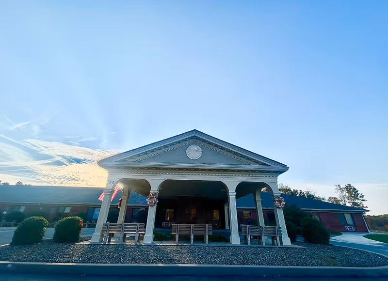 Front view of Edgewood Estates elderly care facility with a covered entrance and flags.