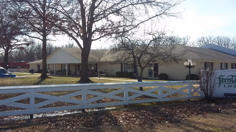 Exterior view of Fern Terrace Lodge of Murray: single-story building, white fence, and bare trees.