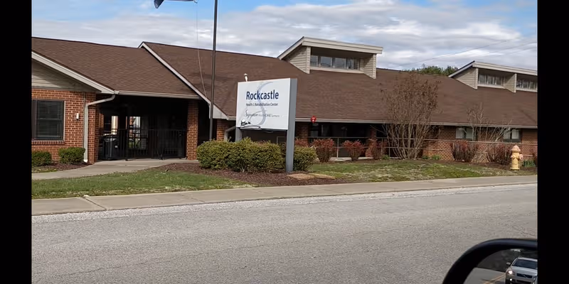 Exterior view of Rockcastle Health and Rehabilitation Center with sign, brick building, and landscaping.