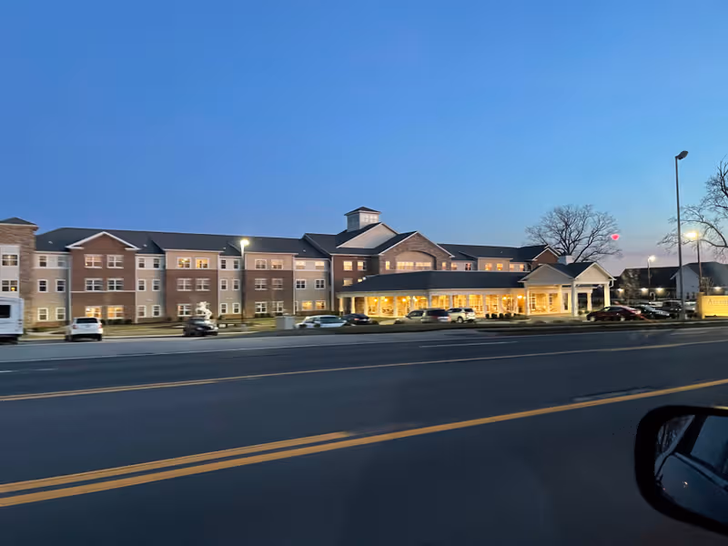 Exterior view of Arcadia Senior Living Bowling Green building along a busy street at dusk.