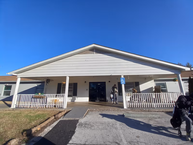 Front view of Christian County Manor with porch, ramp, and people at entrance.