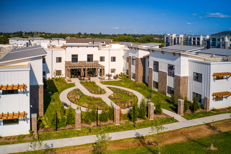 A Preston Greens Senior Living campus with white buildings and a central landscaped courtyard.