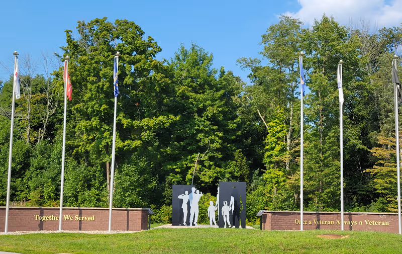 Exterior view of Radcliff Veterans Center entrance with flagpoles, brick walls, and silhouette sculptures.