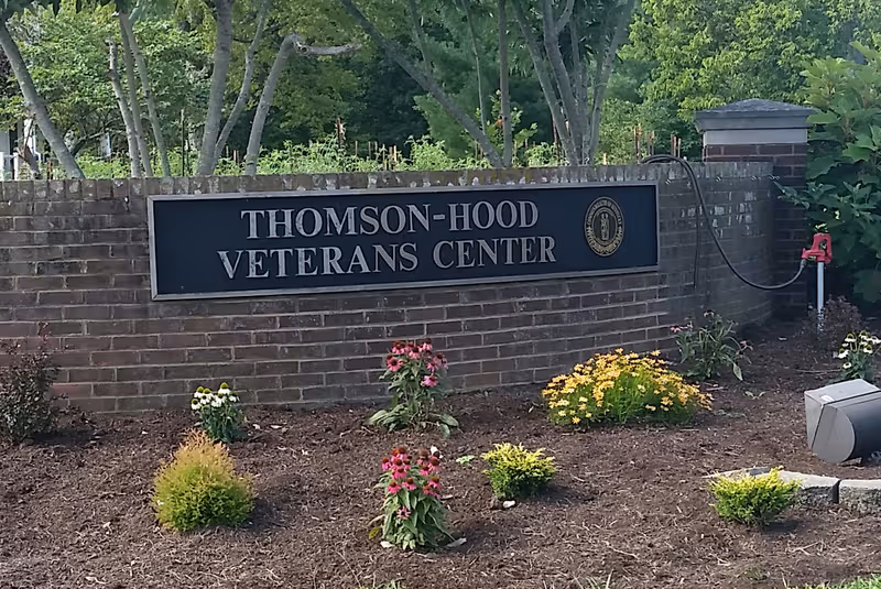 Exterior brick sign wall for Thomson-Hood Veterans Center with flowers.