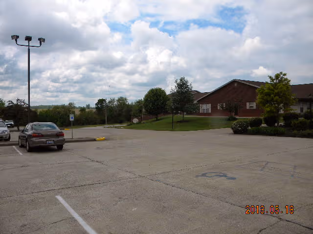 Parking lot and front exterior of Twin Oaks Assisted Living building with a car parked.