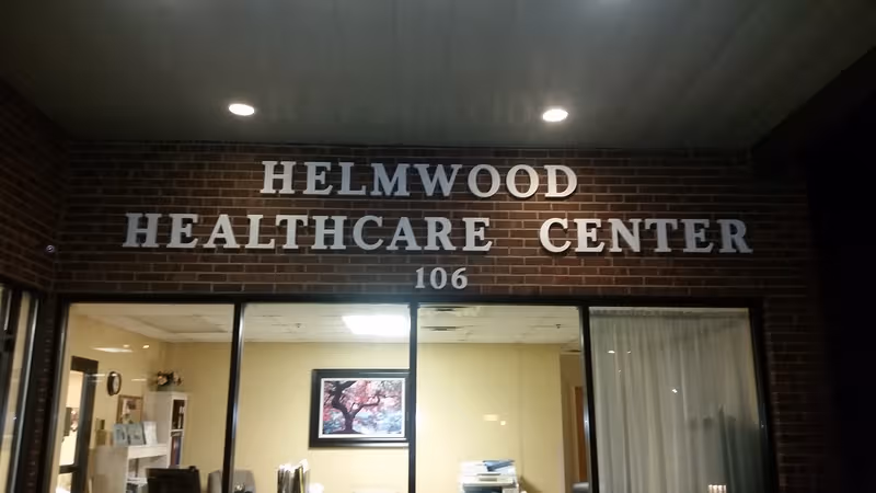 Exterior view of Helmwood Healthcare Center entrance with brick facade and glass doors.