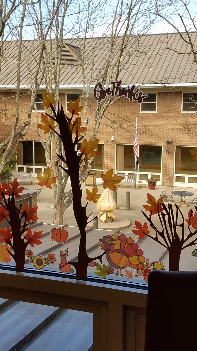 Exterior view of Thomson-Hood Veterans Center courtyard seen through a window with autumn decals.