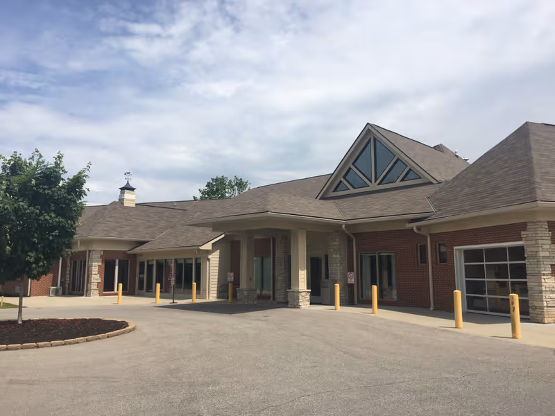 Exterior view of a senior living facility entrance with brick walls and a covered drop-off.