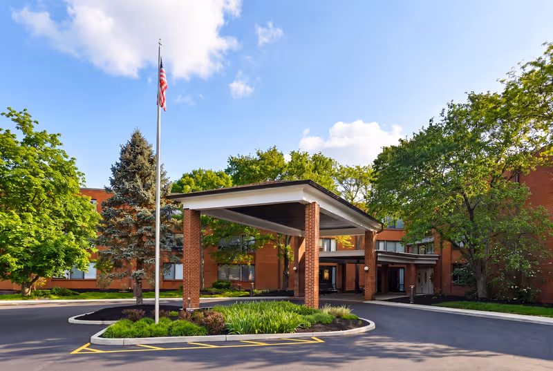 Celebration Villa of Highland Crossing exterior: brick building, covered entrance, flagpole, and trees.