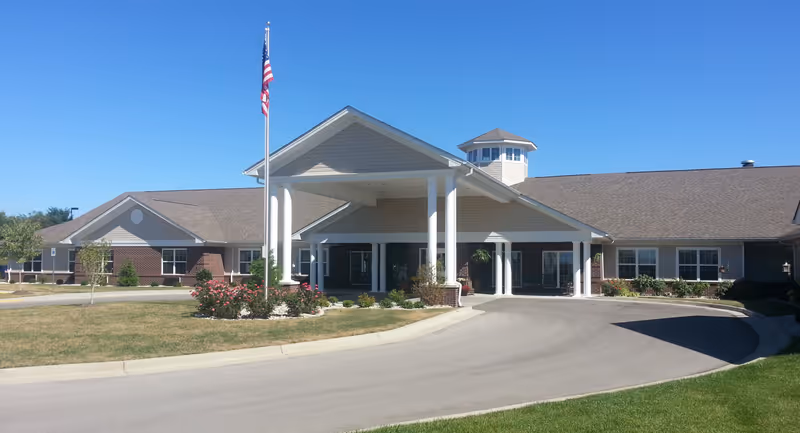Exterior view of The Willows at Citation with a covered entrance, flagpole, and landscaped grounds.