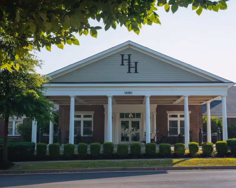 Front view of Hallmark House senior living facility with brick facade and white columns.