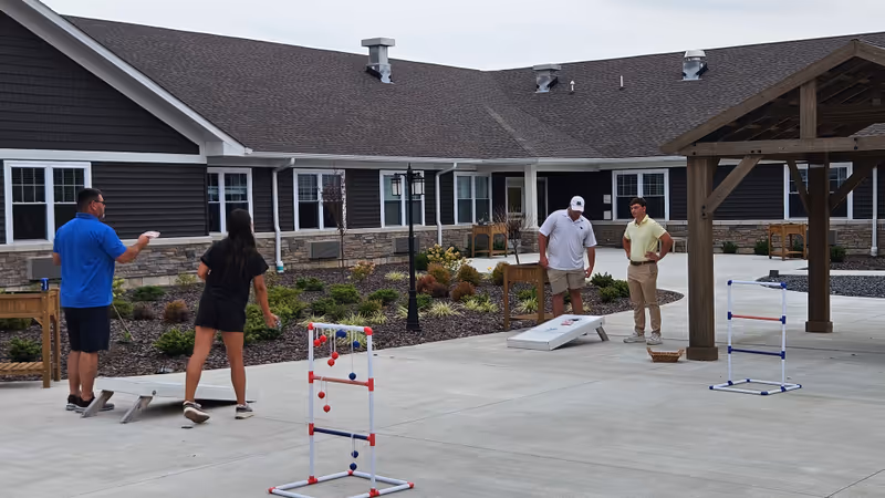 Residents and staff play a game in the outdoor courtyard of Charter Senior Living of Paducah.