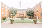 Nursing home courtyard framed by brick buildings with trees, lawn, and planters.