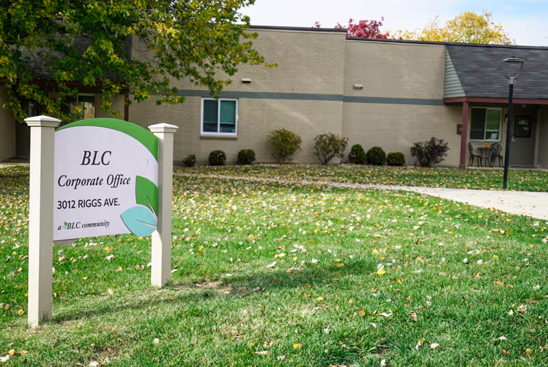 Front exterior of a Baptist Life Communities building with a green sign on the lawn.