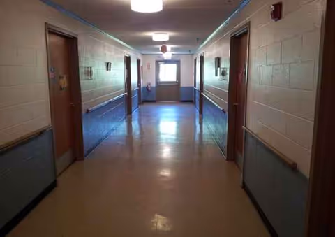 Long hallway inside a senior living facility with doors on both sides.