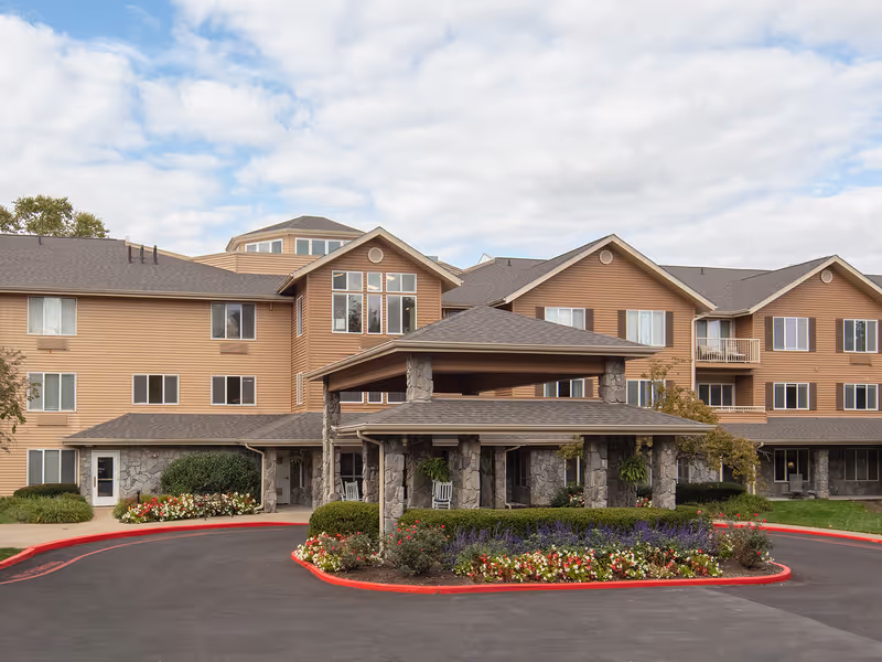 Exterior view of Holiday Hartland Hills senior living facility with stone entry and landscaped circle