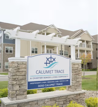 Front exterior view of Calumet Trace senior living community with a stone sign.