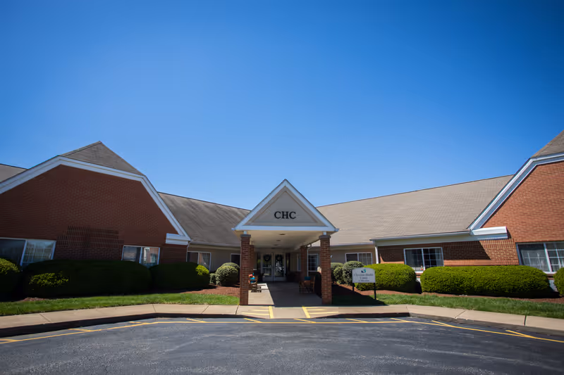 Village Manor senior living facility entrance with peaked roof and landscaping.