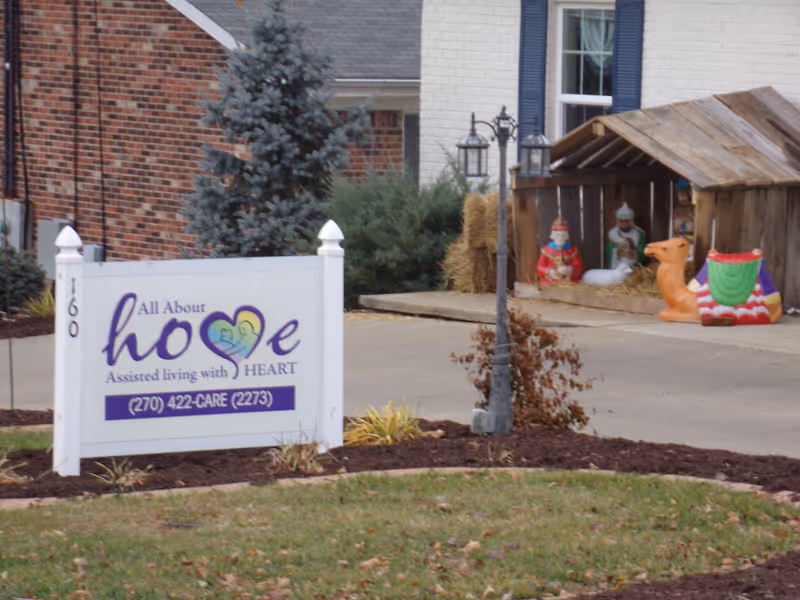 Exterior view of the All About Home Assisted Living sign in front of a building.
