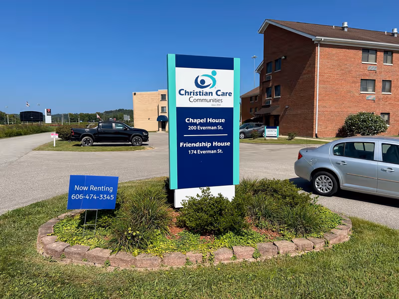 Christian Care Communities sign for Chapel House and Friendship House with brick building in background.