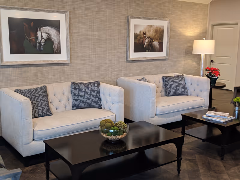 Two light gray tufted sofas with patterned pillows in a modern living room lounge.