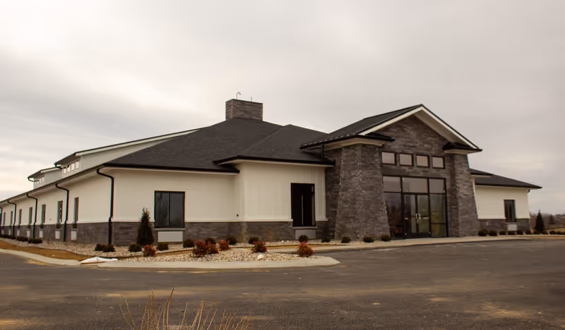 Exterior view of Peridot Senior Living, a single-story building with stone entry and wide glass doors.