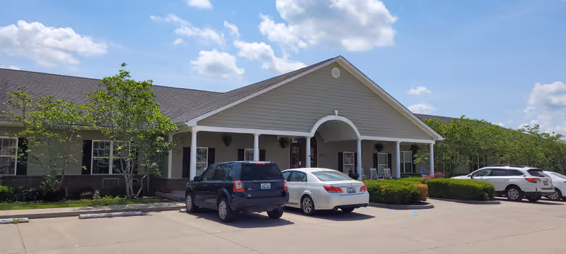 Arcadian Cove Senior Living facility exterior with arched entrance and parked cars.