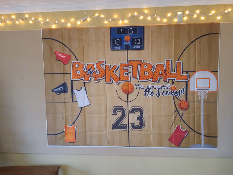 Indoor mural depicts a basketball court with a scoreboard and string lights along the wall.