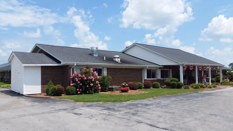 Single-story brick building with white siding, manicured shrubs, and a covered front entrance.