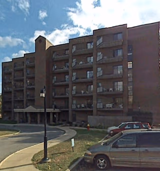 Exterior view of Arnold Tower senior living facility with balconies and parked cars.