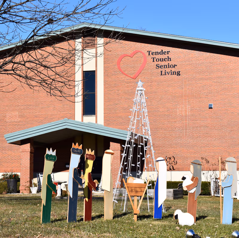 Brick Tender Touch Senior Living building with heart logo and holiday decorations in front yard