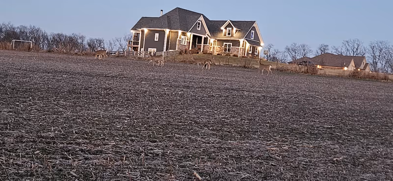 A large senior living facility with a house-like front sits on a field with deer.