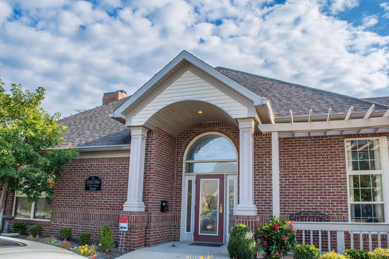 Exterior view of Cornell Trace Club House front entrance with brick facade and columns.
