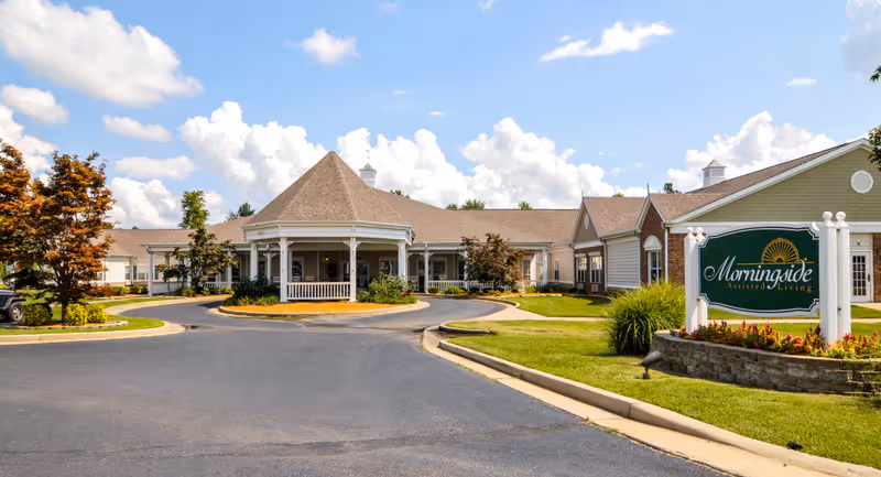 Front exterior of a single-story assisted living building with a circular driveway, landscaping, and a large sign reading 'Morningside Assisted Living'.