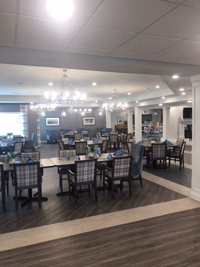 Spacious dining room in a senior living facility with set tables.